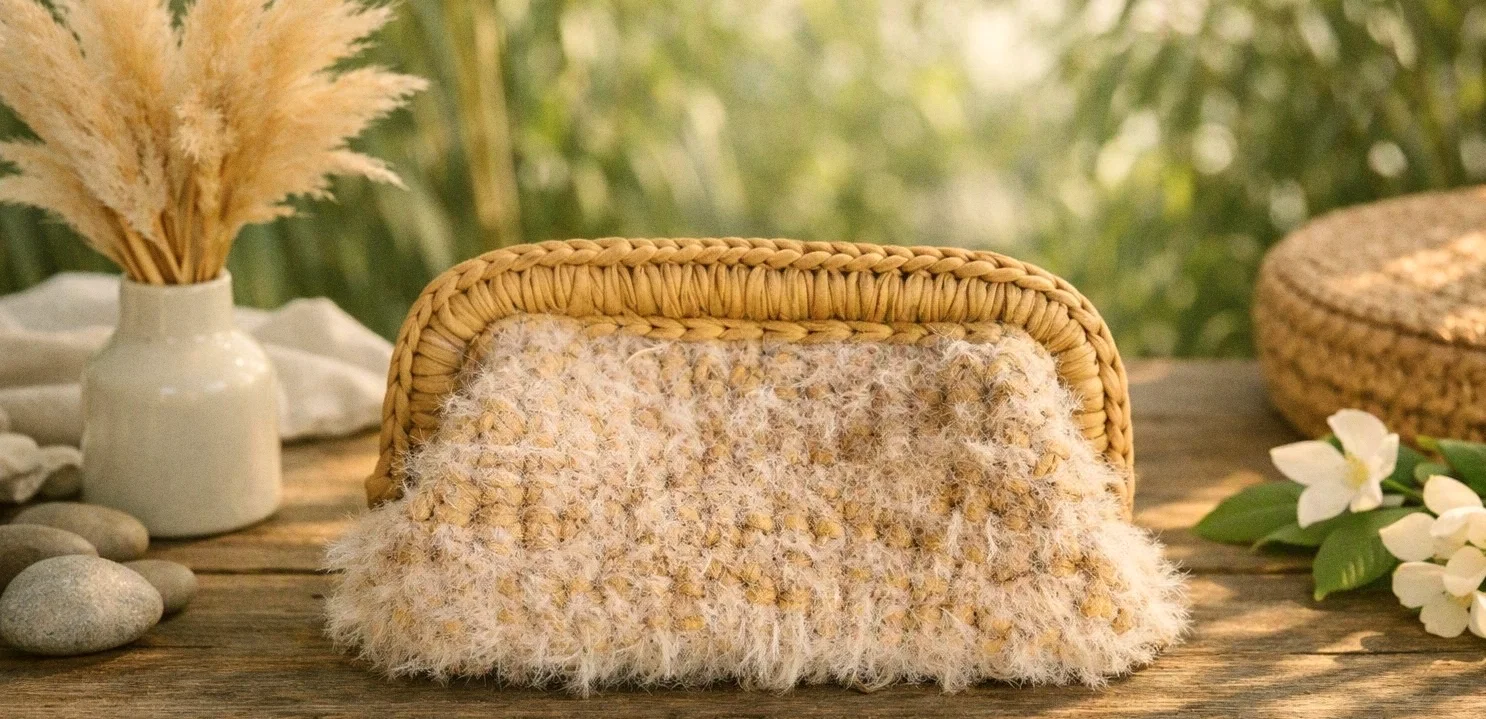 Clutch Eolia color latte su un tavolo di legno, con pampas e fiori bianchi