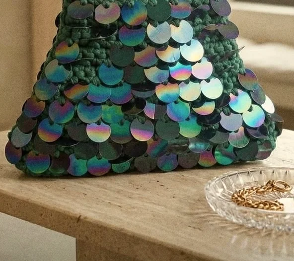 Paillettes iridescenti sull’intreccio verde smeraldo