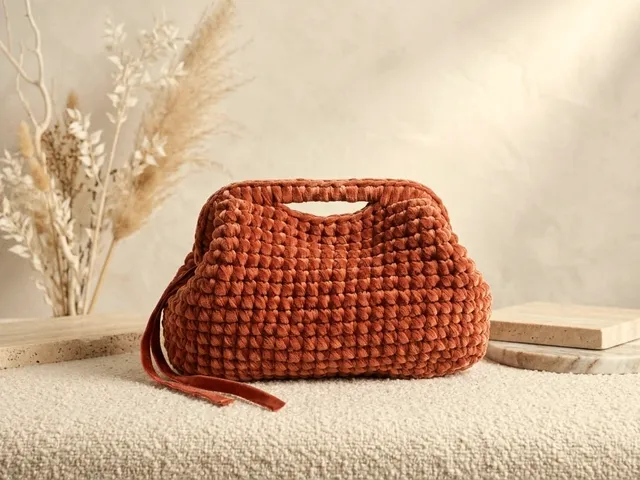 Pochette Tindari in velluto terracotta su un tessuto bouclé, con rami secchi e pampas